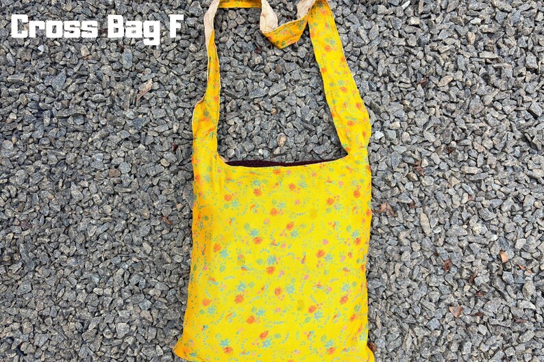 Pu&ograve; includere: Borsa a tracolla gialla con un motivo floreale arancione e blu. La borsa ha una lunga tracolla ed &egrave; realizzata in un tessuto leggero. Il testo "Cross Bag F" &egrave; visibile in alto.