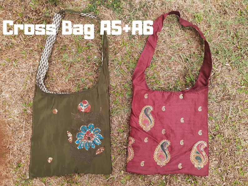 Pu&ograve; includere: Due borse a tracolla. Una &egrave; verde oliva con ricami floreali e un cinturino fantasia. L'altra &egrave; bordeaux con ricami paisley. Il testo "Cross Bag AS+A6" &egrave; in alto.