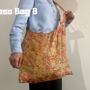 Pu&ograve; includere: Una borsa a tracolla con un motivo ripetuto nelle tonalit&agrave; del rosa, arancione e marrone. La borsa &egrave; etichettata "Cross Bag B" in testo bianco. La borsa &egrave; indossata a spalla.