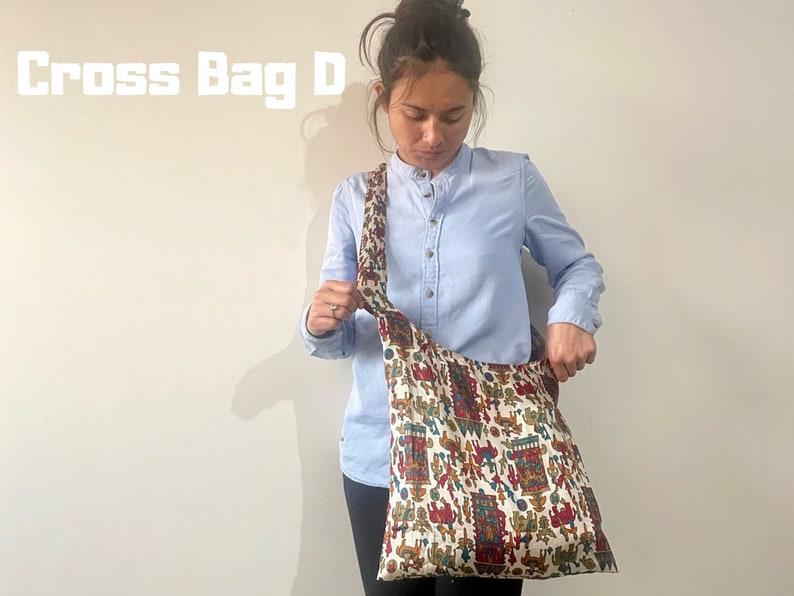 Pu&ograve; includere: Una borsa a tracolla color crema con un motivo colorato di figure e forme. La borsa ha una lunga tracolla ed &egrave; indossata da una persona che indossa una camicia azzurra. Il testo "Cross Bag D" &egrave; visibile nell'immagine.