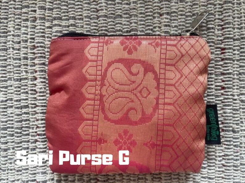 K&ouml;nnte beinhalten: Eine rote und goldene Sari-Tasche mit Rei&szlig;verschluss und einem gr&uuml;nen "greenliving"-Etikett. Die Tasche hat ein traditionelles indisches Design.