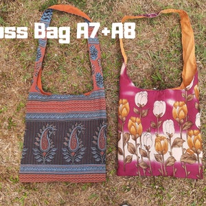 Pu&ograve; includere: Due borse a tracolla con lunghe cinghie sono appoggiate sull'erba. Una borsa presenta un motivo paisley nei toni del rosso, nero e blu. L'altra borsa mostra un design floreale con tulipani bianchi e gialli su sfondo bordeaux. Il testo "Cross Bag A7+A8" &egrave; visibile.