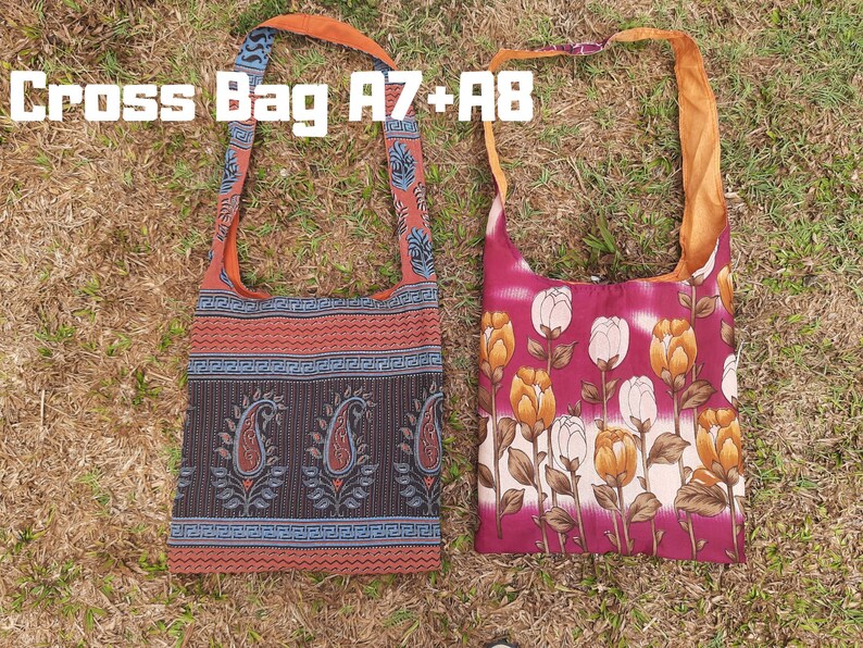 Pu&ograve; includere: Due borse a tracolla con lunghe cinghie sono appoggiate sull'erba. Una borsa presenta un motivo paisley nei toni del rosso, nero e blu. L'altra borsa mostra un design floreale con tulipani bianchi e gialli su sfondo bordeaux. Il testo "Cross Bag A7+A8" &egrave; visibile.