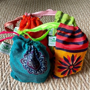 Pu&ograve; includere: Cinque sacchetti a cordoncino colorati con un logo a foglia verde e il testo "frog india.com". I sacchetti sono realizzati in tessuto con diversi motivi, tra cui strisce, fiori e paisley.