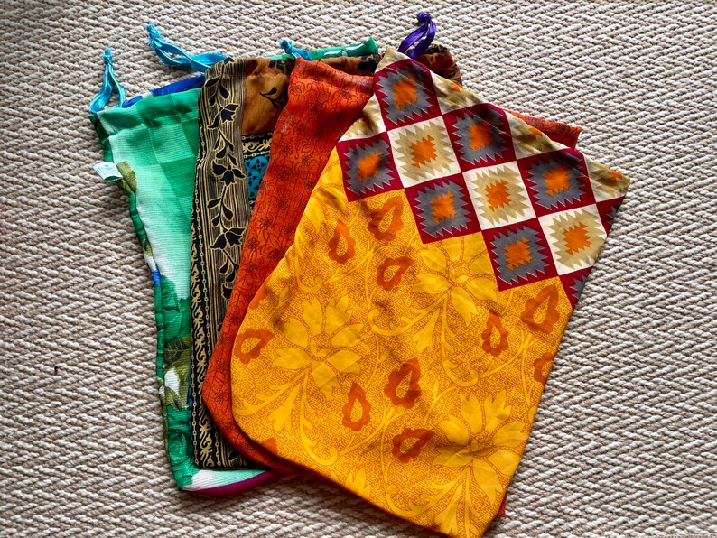Pu&ograve; includere: Cinque sacchetti di stoffa con coulisse di diversi colori e motivi. I sacchetti sono realizzati con sari riciclati e sono perfetti per trasportare generi alimentari, articoli da toeletta o altri piccoli oggetti.