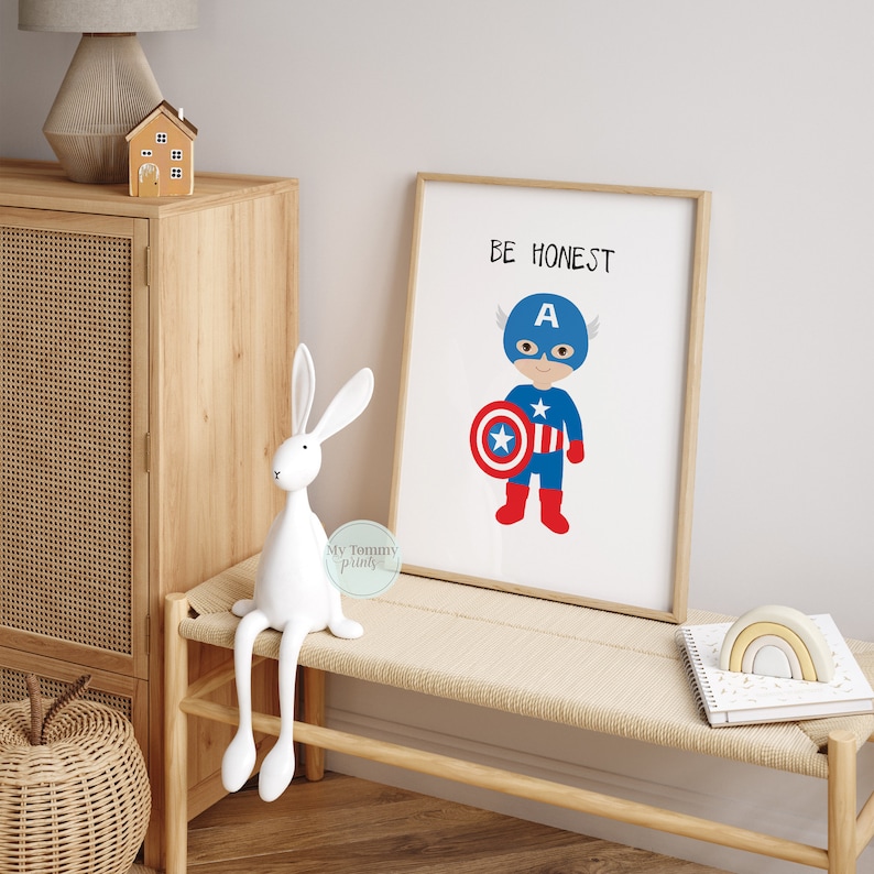 Op de afbeelding: Een ingelijst print met een cartoonillustratie van Captain America, een superheld, die zijn schild vasthoudt. De print heeft de tekst "BE HONEST" bovenaan en de letter "A" op de borst van de superheld.
