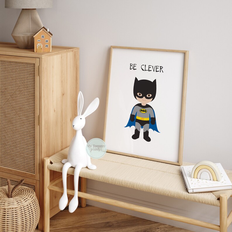 Op de afbeelding: Een ingelijst print met een zwart en geel cartoon superheldenfiguur dat een blauwe cape en een zwart masker draagt. De tekst "BE CLEVER" is boven het figuur gedrukt.