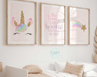 May include: Three framed wall art prints with light pink backgrounds. The left print shows a unicorn face with a gold glitter horn. The centre print features the text "She leaves a little Sparkle wherever she goes". The right print shows a shooting star.