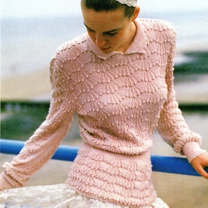 May include: A pink knitted jumper with a textured pattern and a white headband. The jumper has a collared neckline and long sleeves.