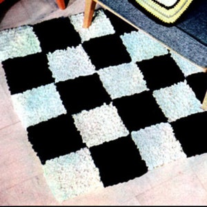 Puede incluir: Una alfombra de cuadros negros y blancos con una textura esponjosa. La alfombra est&aacute; hecha de hilo y tiene un patr&oacute;n de tablero de ajedrez.