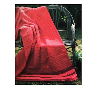 May include: A vibrant red crochet blanket featuring a textured stitch pattern throughout. The blanket has a solid red body with a darker red horizontal stripe detail near the bottom edge, creating a simple and clean visual design.