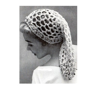 May include: A vintage-style, open-weave crochet head covering. The white headpiece features a netted design with decorative embellishments around the crown and a long, draped section. The image is in black and white, highlighting the texture and detail of the handmade item.
