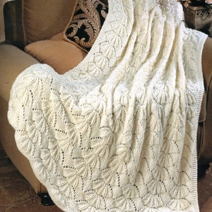 May include: A white crocheted throw blanket with a delicate leaf pattern, draped over a brown armchair with a patterned pillow.