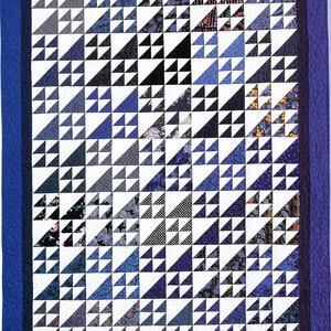 May include: A quilt made of blue and white fabric with a geometric pattern of triangles. The quilt is framed with a dark blue border.