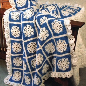 May include: A crocheted throw blanket with a white and blue snowflake pattern. The blanket has a white crocheted border with a scalloped edge.