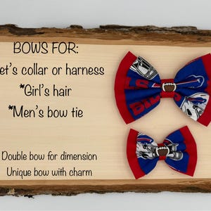 May include: Two fabric bow ties with a football and team logo design. The larger bow tie is red and blue with a white football and the smaller bow tie is red and blue with a white football. The text on the wooden sign reads "BOWS FOR: *Pet's collar or harness *Girl's hair *Men's bow tie Double bow for dimension Unique bow with charm"