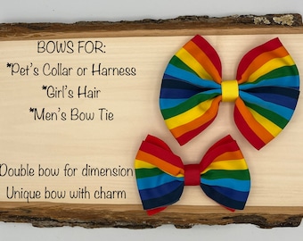 Può includere: Due fiocchi di stoffa arcobaleno, uno più grande dell'altro, su una superficie di legno. Il testo "BOWS FOR:" è scritto sopra i fiocchi, seguito da un elenco di usi per i fiocchi: "*Pet's Collar or Harness", "*Girl's Hair", "*Men's Bow Tie". Il testo "Double bow for dimension" e "Unique bow with charm" è scritto sotto i fiocchi.