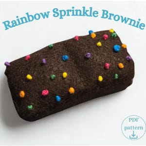 May include: A rectangular dark brown felt brownie featuring small, colourful embroidered dots in yellow, blue, pink, green, and purple. The text Rainbow Sprinkle Brownie is arched above the object, and a PDF pattern icon is in the corner.