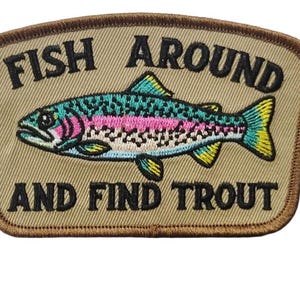May include: Embroidered patch with a trout illustration. The fish is teal, pink, and yellow, with the text "FISH AROUND AND FIND TROUT" in black. The patch has a tan background and a brown border.