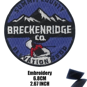 May include: Embroidered patch with a blue background and white mountains. The text "Summit County Breckenridge Co. Elevation 9600" is embroidered in white. The patch is 2.67 inches in diameter.