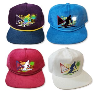 May include: Four corduroy baseball caps with a colourful graphic of a skier on the front. The caps are in blue, white, red, and purple.