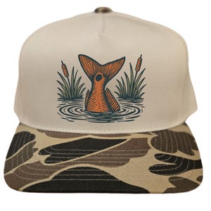Op de afbeelding: Beige en camouflage baseballcap met een oranje visstaartafbeelding in water met riet. De cap heeft een platte klep met een camouflagepatroon en een beige kroon. De afbeelding is een gedetailleerde illustratie.