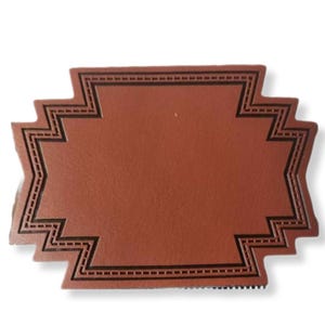 Puede incluir: Un parche de cuero marrón con un borde decorativo cosido en negro. El borde tiene un patrón de zigzag.