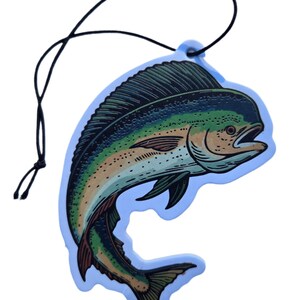 May include: A blue air freshener shaped like a fish, featuring a detailed illustration in shades of green, yellow, and brown. The fish is outlined in black and has a black string for hanging. The air freshener has a light blue border.
