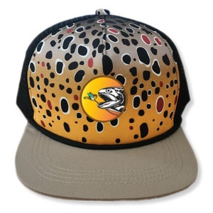 May include: A brown, black, and orange trucker hat with a brown trout with a fly in its mouth on the front. The hat has a black mesh back and a brown brim.