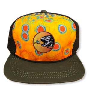 May include: A yellow, orange, and blue tie-dye trucker hat with a black mesh back. The hat features a circular patch with a trout and a fly.