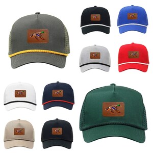 Puede incluir: Un conjunto de diez gorras de camionero de varios colores, cada una con un parche de un pato silvestre en la parte delantera. Las gorras están hechas de un material de malla y tienen una visera curvada.