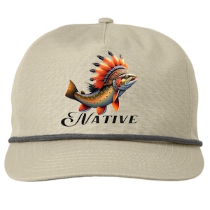 May include: Tan baseball cap with a Native American-inspired fish graphic. The fish is orange, yellow, and blue, wearing a feathered headdress. The word "NATIVE" is written in black script below the fish. The cap has a gray rope trim.
