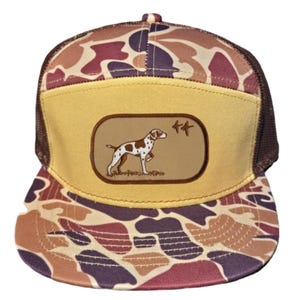 以下が含まれることがあります： 茶色とベージュの迷彩柄のトラッカーハット。前面には、茶色と白の犬と2羽の鳥がベージュのパッチに刺繍されている。
