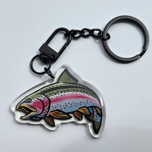 Op de afbeelding: Een zwarte metalen sleutelhanger met een transparante acryl hanger met een kleurrijke regenboogforel illustratie.