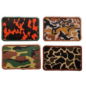 May include: Four different camouflage fabric patches with brown stitching around the edges. The patches are in orange, brown, green, and black camouflage patterns.