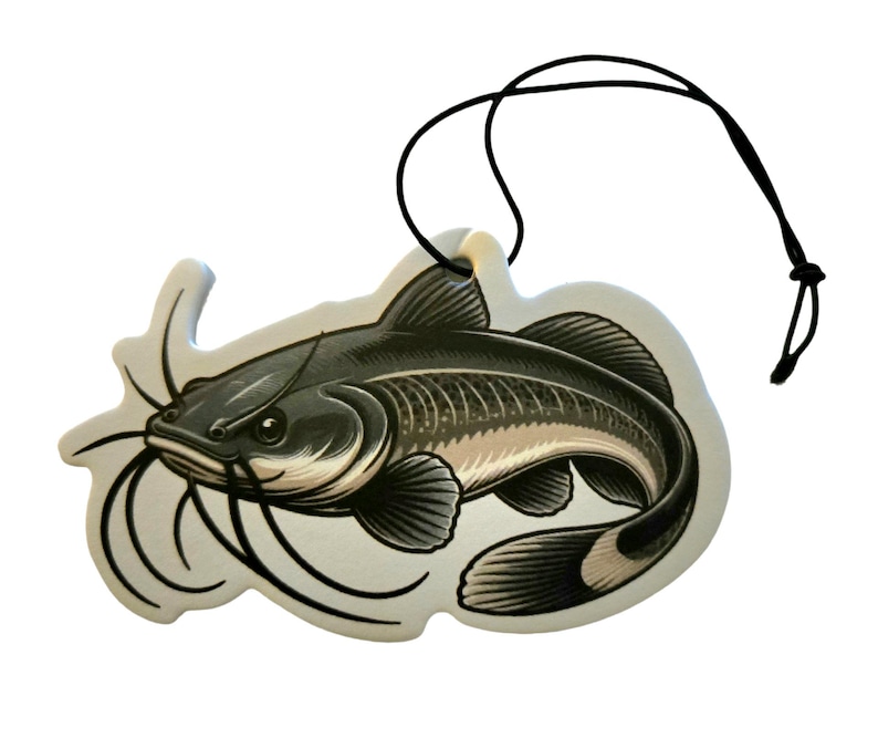 May include: A decorative air freshener shaped like a catfish. The air freshener features a detailed illustration of the fish in shades of gray and beige, with long whiskers and a black string for hanging.