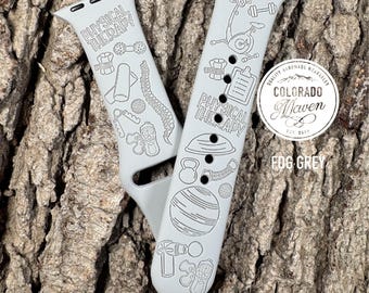 May include: A fog grey silicone watch band featuring black line art illustrations of physical therapy equipment, including a stationary bike, dumbbells, a spine, a kettlebell, a stability ball, and a massage gun, with the text PHYSICAL THERAPY.