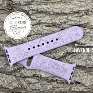 May include: A lavender silicone watch band featuring engraved line art icons related to occupational therapy, including a wheelchair, crutches, a clipboard, and medical symbols. The text "OCCUPATIONAL THERAPY" is engraved on the lower strap section.