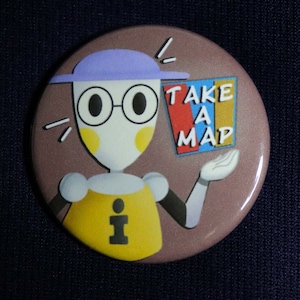 Könnte beinhalten: Ein brauner Knopf mit einer Comicfigur, die einen lila Hut und eine Brille trägt. Die Figur hält ein Schild mit der Aufschrift "Nehmen Sie eine Karte".