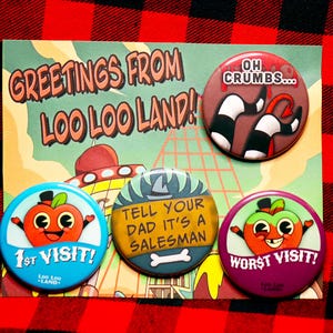 Puede incluir: Una postal con el texto "GREETINGS FROM LOO LOO LAND!" y cuatro botones coloridos. Los botones presentan personajes de dibujos animados de manzanas y frases como "1st VISIT!" y "WORST VISIT!" sobre un fondo a cuadros rojo y negro.