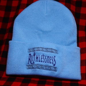Puede incluir: Un gorro azul claro con un logotipo bordado en azul marino que dice "Ruthlessness" en una fuente decorativa.