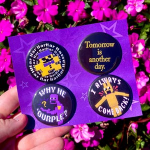 Puede incluir: Cuatro botones negros con texto y diseños de personajes de dibujos animados. Un botón dice "Tomorrow is another day". Otro dice "I ALWAYS COME BACK!". Los otros dos botones tienen el texto "Har Har Har" y "WHY HE 'OURPLE?"
