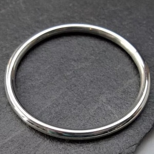 Puede incluir: Un brazalete de plata simple con un acabado liso y pulido.