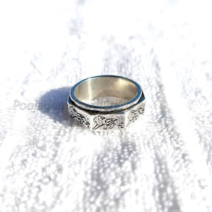 May include: A silver spinning ring with a lion design. The ring is made of metal and has a smooth, polished finish.