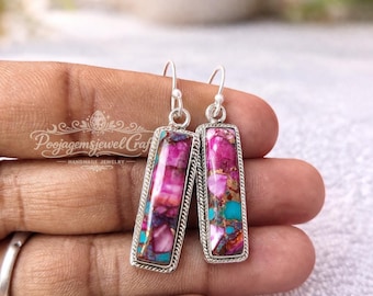 Puede incluir: Pendientes rectangulares con una vibrante mezcla de piedras rosas, moradas y turquesas engastadas en un marco plateado. Los pendientes tienen un borde texturizado y un diseño de gancho simple. Joyería hecha a mano.