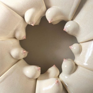 May include: A close-up of a ceramic sculpture with a circular design. The sculpture is made of white ceramic and has a smooth, glossy finish. The sculpture is shaped like a series of overlapping circles, each with a raised, rounded centre.