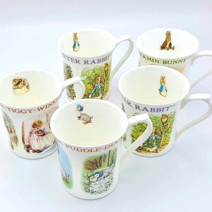 May include: Set of six white ceramic mugs with colorful illustrations of Beatrix Potter characters. The mugs feature Peter Rabbit, Benjamin Bunny, Jemima Puddle-Duck, Mrs. Tiggy-Winkle, and two other characters.