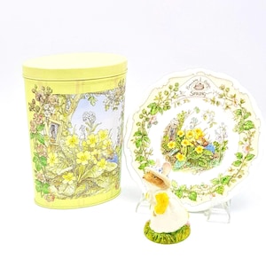 May include: A yellow and green tin with a floral design and a Beatrix Potter character. A matching plate with a floral design and the words "Remembering Beatrix Potter Spring" and a figurine of a mouse wearing a hat.