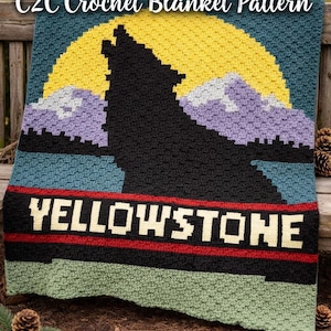 May include: A crocheted blanket featuring a black wolf silhouette howling at a yellow sun, with purple mountains and the word "Yellowstone" in white. The blanket is made with various colors and textures.