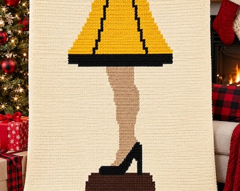 May include: A rectangular cream-colored crochet blanket featuring a centered graphic design of a leg lamp. The lamp has a yellow shade with black trim, a tan leg, a black high-heeled shoe, and a brown rectangular base, all rendered in crochet.